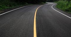 Winding asphalt road with a central yellow line and white edge marking