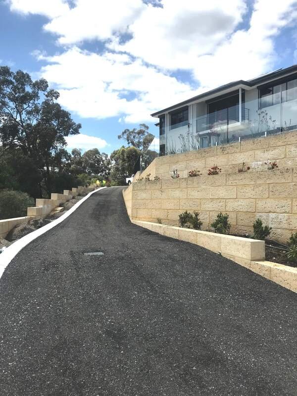 Asphalt road beside residential property with sandstone wall in Brisbane