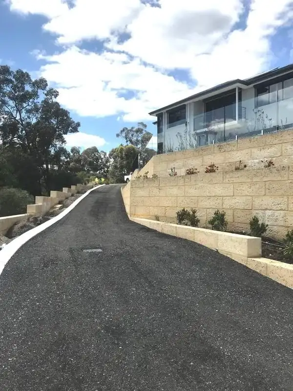 Asphalt road beside residential property with sandstone wall in Perth