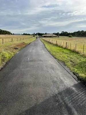 Long residential asphalt driveway with smooth bitumen surface surrounded by green farmland in Perth